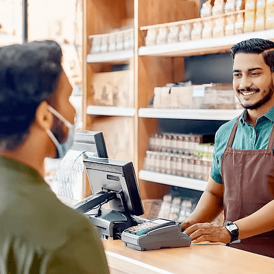 A shopkeeper serving a customer across the counter of a small store